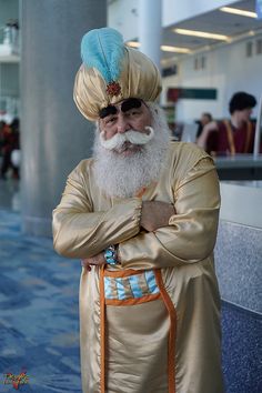 a man with a long white beard wearing a gold outfit and blue turban