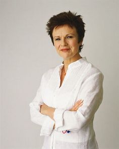 an older woman with her arms crossed posing for a photo in front of a white background