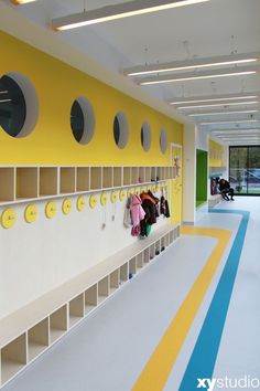 a yellow and white room with several coats hanging on the wall next to lockers