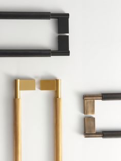 an assortment of brass and black objects on a white surface, including two square handles