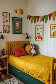 a child's bedroom with yellow bedding and posters on the wall above it