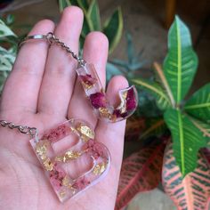 a hand holding two pieces of glass with gold flakes on them and the letter e in it