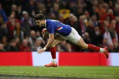 a rugby player dives for the ball in front of an onlooker