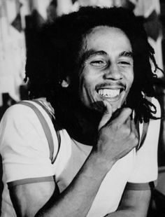 a black and white photo of a man with dreadlocks smiling at the camera