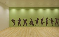 the silhouettes of people dancing in an empty room with green walls and wood flooring