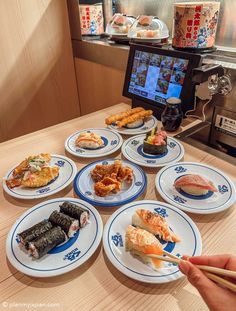 a person holding chopsticks in front of plates with sushi on them and an appliance