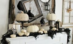 a mantel decorated with white pumpkins, black feathers and other halloween decor items