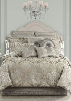 the bed is made and has many pillows on it, including one with a chandelier