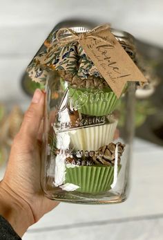 a person holding up a jar filled with cupcakes