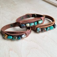 Genuine chunks of African Turquoise is sewn on to a genuine leather cuff with two adjustable snaps. Please note, all stones are genuine. They come in a variety of shapes and colors shown in multiple pictures. Entire length of bracelet is 3/4" by 9" Adjusts with snaps from Approx. 7.25" to 7.75" Although your bracelet will resemble the photo, each piece is created by hand, so no two are identical.Thank you for visiting The Jewelry Junkie! Adjustable Leather Strap Bohemian Cuff Bracelet, Adjustable Bohemian Cuff Bracelet With Leather Strap, Bohemian Turquoise Leather Bracelet, Turquoise Bohemian Leather Bracelet, Adjustable Leather Cuff Bracelet For Festival, Rustic Turquoise Leather Bracelet, Southwestern Leather Bracelet For Festival, Adjustable Bohemian Leather Cuff Bracelet, Bohemian Turquoise Leather Cuff Bracelet