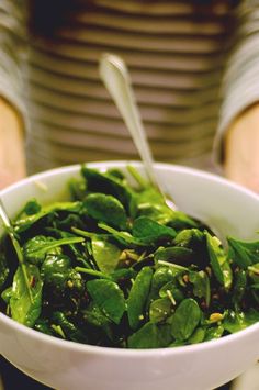 a white bowl filled with green vegetables on top of a table