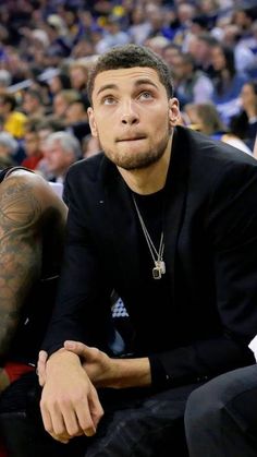 a man sitting on top of a basketball court next to another person in the stands