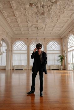 a man in a suit and tie standing on a hard wood floor with chandelier