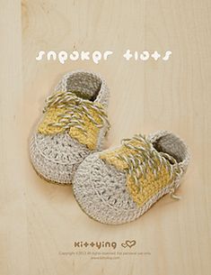 a pair of crocheted baby shoes sitting on top of a wooden floor next to a sign