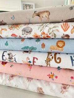 a stack of cloths with animals and letters printed on them, all in different colors