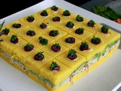 a square cake on a white plate topped with chocolate covered strawberries and garnishes