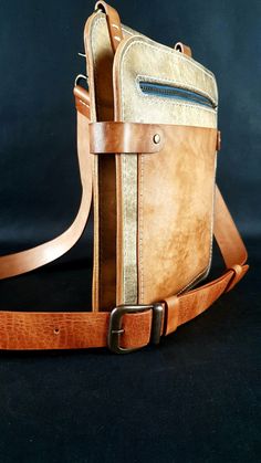 a brown leather messenger bag sitting on top of a black surface