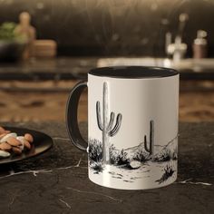 a white and black coffee mug sitting on top of a counter next to a plate