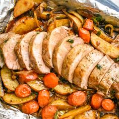 sliced pork, potatoes and carrots in foil on top of a white tablecloth