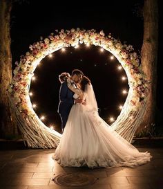 a bride and groom standing in front of a wedding arch with fairy lights on it