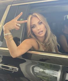 a woman is sitting in the back of a car and pointing at something with her finger