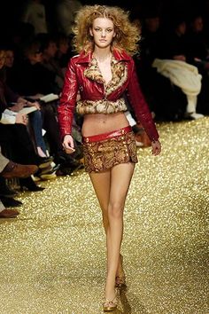 a model walks down the runway in a red leather jacket and gold sequin skirt