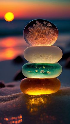 three rocks stacked on top of each other with the sun setting in the background