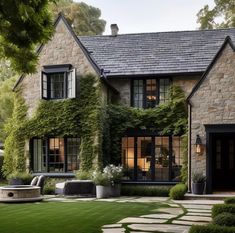 a stone house with ivy growing on it's walls and landscaping around the front door