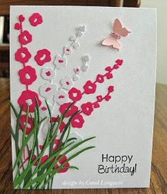 a happy birthday card with red flowers and a pink butterfly on the front, sitting on a wooden table