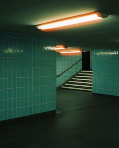 an empty room with green tiles and stairs