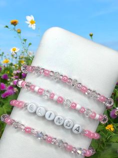 Embrace your inner good witch with this enchanting Glinda-inspired bracelet set! These delicate beaded bracelets feature a magical combination of soft pink and sparkling crystal beads, reminiscent of Glinda's iconic pink bubble and shimmering wand. The set includes: A personalized name bracelet spelling out "GLINDA" in white letter beads Three coordinating pink and crystal beaded bracelets Perfect for: Wizard of Oz fans Good witch cosplay Adding a touch of magic to any outfit Gifting to your fairest friend Are you feeling wicked or pretty? Choose the light side with these whimsical Glinda bracelets that are sure to make you feel like the Good Witch of the North! #GlindaTheGoodWitch #WizardOfOz #BeadedBracelet #PersonalizedJewelry #MagicalAccessories #PinkSparkle #GoodWitchVibes #OzInspired Magical Handmade Bracelets As A Gift, Personalized Pink Whimsical Bracelet, Personalized Whimsical Pink Bracelet, Whimsical Personalized Pink Bracelet, Whimsical Beaded Charm Bracelet For Gift, Whimsical Beaded Bracelets As A Gift, Whimsical Round Beaded Bracelets As Gift, Cute Beaded Crystal Bracelet For Gift, Cute Beaded Crystal Bracelet As Gift