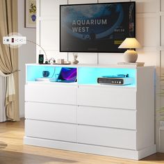 a white entertainment center with blue lights on the side and a flat screen tv mounted above it