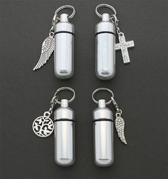 three bottles with charms attached to them on a black surface, one has a cross and the other is a keychain