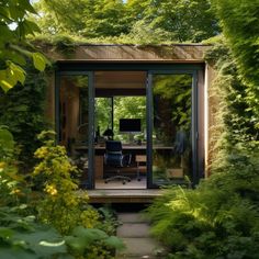 a small office in the middle of some trees and bushes with a computer on it