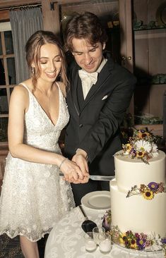 a man and woman cutting into a wedding cake