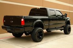 a black pickup truck parked in front of a tan building with red stripes on the side