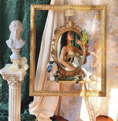 a woman is looking into a mirror in a room with green wallpaper and gold trim