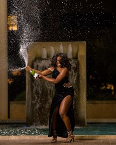 a woman in a black dress spraying water on herself