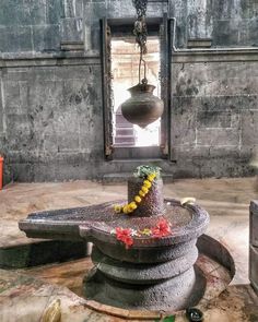 a statue with flowers on it in the middle of a room next to a window