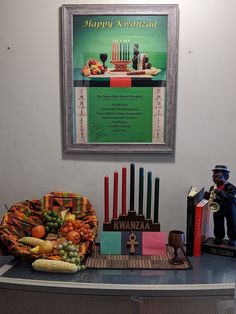 a table topped with candles and fruit on top of a blue counter next to a framed poster