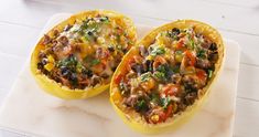 two stuffed acorns on a white platter with tomatoes and green garnishes