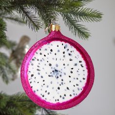 a pink ornament hanging from a christmas tree with white and black speckles