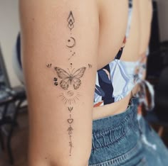 the back of a woman's shoulder with an arrow and butterfly tattoo on it