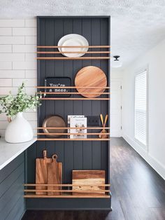 the shelves in this kitchen are organized with wooden cutting boards, plates and utensils