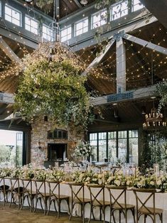 the reception tables are set up with white linens and greenery hanging from the ceiling