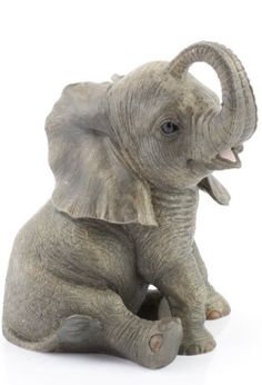 an elephant figurine sitting on the ground with its trunk in it's mouth