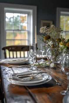 a wooden table topped with plates and vases filled with flowers on top of it