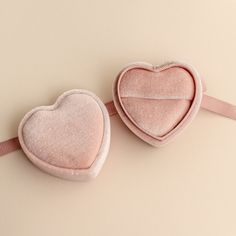 two pink heart shaped cushions sitting next to each other on top of a beige surface