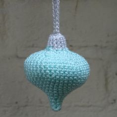 a crocheted blue ornament hanging from a hook on a brick wall