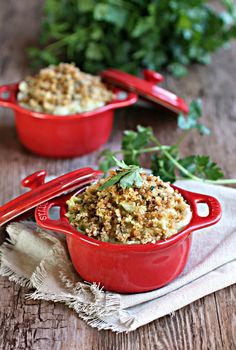 two red dishes filled with food sitting on top of a wooden table next to parsley